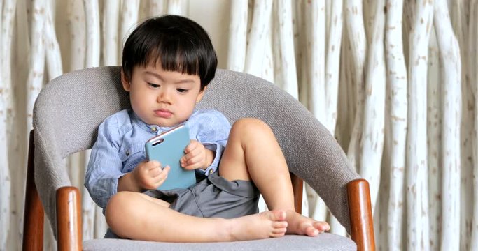 Baby boy watching cartoon on smart phone at home