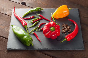 Harvest of different peppers on a slate stone background