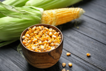 Bowl with corn kernels on wooden background