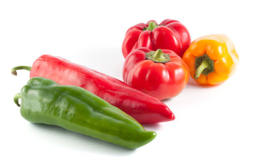 Green, red and yellow peppers on a white background