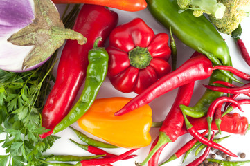 Harvest of different peppers and vegetables on a white background