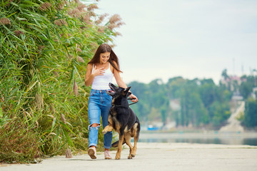 A young girl is walking with a German shepherd dog in the park.