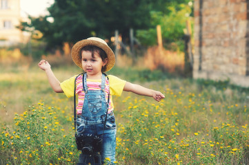 little girl in denim overalls in a field with a camera, the Concept of children's casual wear