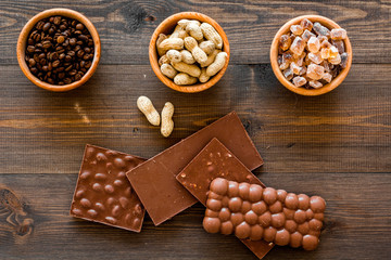 Chocolate with nuts on dark wooden background top view