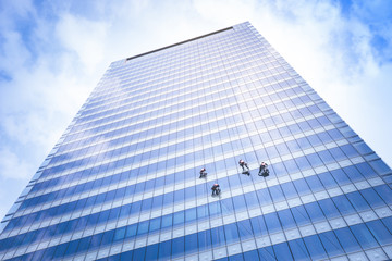 Bangkok ,Thailand - MARCH 30, 2016 : window cleaner working on a glass facade modern skyscraper.Now...