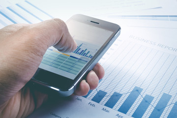 Close up hand of businessman touching smartphone and graph chart  background.business market  concept