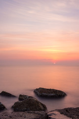 Fototapeta na wymiar Long exposure landscape shot of rocks in the mediterranean at sunrise portrait mode