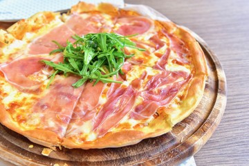 Prosciutto di Parma Pizza Topped with Organic Wild Rocket on a Wooden Plate
