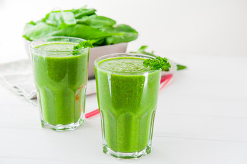 Fresh green Spinach smoothies in glass on the white wooden background. Healthy lifestyle concept. Selective focus. Backlight. Copy space.