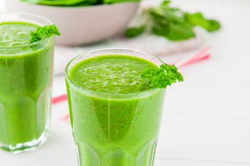 Fresh green Spinach smoothies in glass on the white wooden background. Healthy lifestyle concept. Selective focus. Backlight. Copy space.