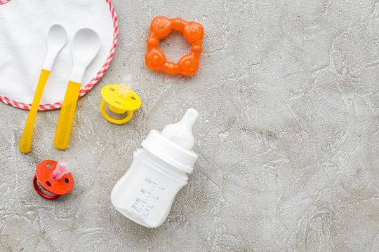Mother care breast milk in bottle and infant formula powdered healthy food with bib for baby feeding on stone background top view mock up