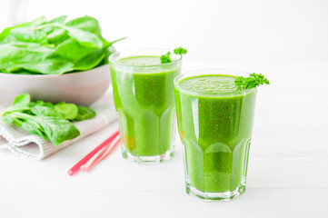 Fresh green Spinach smoothies in glass on the white wooden background. Healthy lifestyle concept. Selective focus. Backlight. Copy space.