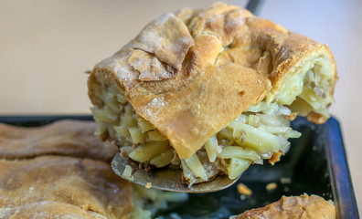 A piece of baked pie with potatoes and stuffing