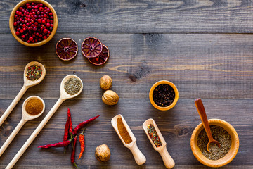 Variety of spices and dry herbs in bowls on wooden kitchen table background top view mock-up