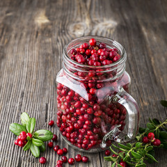 Bottle full of berries fresh ripe northern lingonberry with straws for a cocktail. The concept of healthy drinks from organic products. Top View