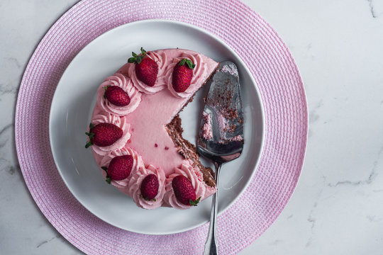 strawberry pink sponge cake on a marble background, a few slices have been cut out