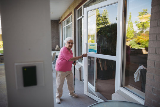 Senior woman opoening door with no smoking sign on it