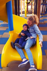 Fototapeta na wymiar Happy family time. Beautiful young mother with her precious little son. Young family having happy time together. Caucasian family playing on the playground. Mother and baby have a great time.