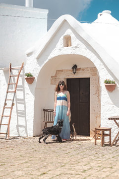 Woman in front of cone-roofed houses of Alberobello