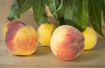 peaches on a brown background. peaches with green leaves. peaches with dark blue grapes