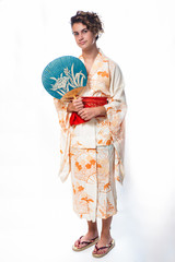 Teen age girl dressed in casual Japanese Yukata kimono holding paper fan on shoulder.