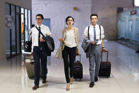 Young startup partners walking down airport corridor with luggage