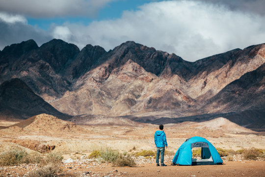 Hiker outside his tent in a rugged mountain landscape