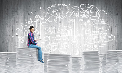 Attractive man sitting on pile of paper documents.