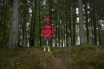 Woman in red coat hiking in the dark forest