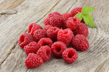 ripe raspberries with green leaf on old wooden table
