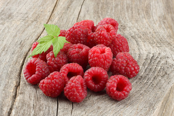 ripe raspberries with green leaf on old wooden table