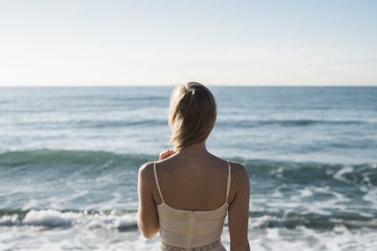 Young woman standing in front of ocean