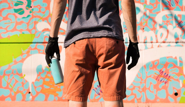 Detail of street artist standing in front of graffiti /look from behind