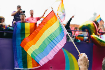 Man's hand waving rainbow flag during pride march
