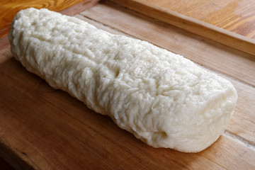 Freshly cooked whole Bohemian bread dumpling on rustic wooden board.