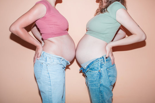 Midsection of women touching their baby bumps