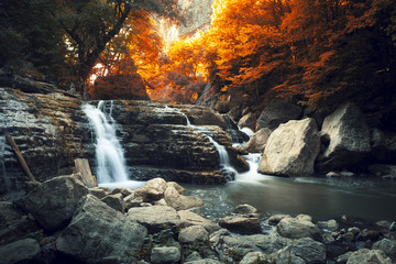 Beautiful waterfall at mountain river in colorful autumn forest