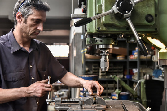 Mature craftsman drilling component in workshop
