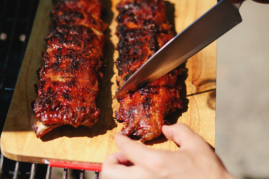 man cuts of pork ribs in barbecue sauce