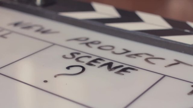 Male hand writing scene number on movie clapperboard by black marker