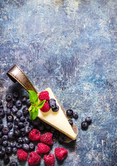 Fototapeta na wymiar Cheesecake with berries on blue slate background.