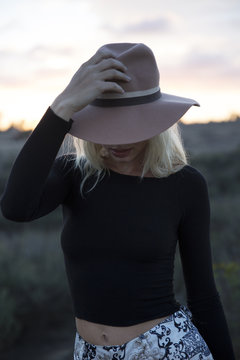 Woman holding her hat during sunset