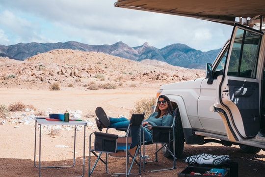woman relaxing in the shade of a car awning on a desert road trip
