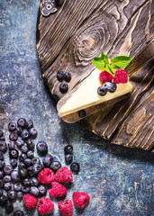 Cheesecake with berries on blue slate background.