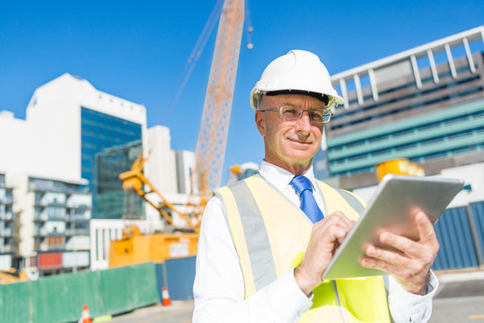Construction manager controlling building site and tablet device in his hands