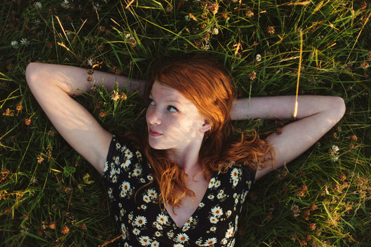A teenage girl laying in a field in the summertime