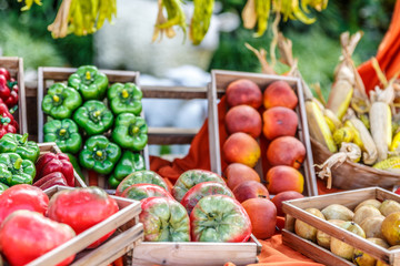 Variety of peppers and tomatoes placed in baskets next to other vegetables and fruits, in a market