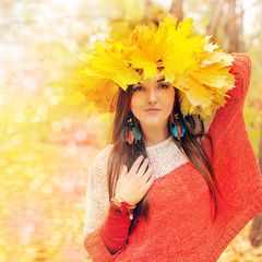 Beautiful smiling woman with wreath of maple leaves on a head