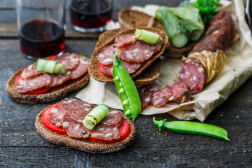 rye sandwich with sausage and tomatoes on wood table.