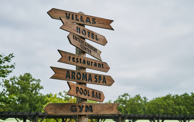 Wooden street signs in the recreation center. Blank street sign post. Crossroad signpost with directions to villas, hotel, entertainment center, restaurant, aroma spa, pool bar and gym